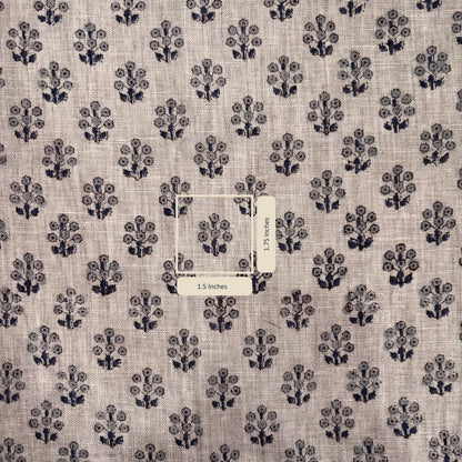 Fabric with a subtle pattern of small black floral designs on a grey background, with a label in the center.