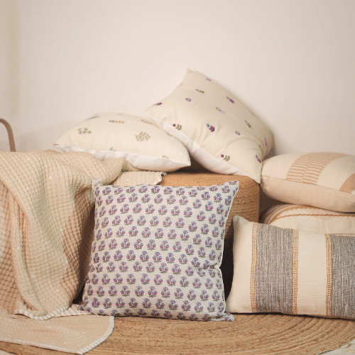 Collection of patterned pillows on a textured surface with a neutral background