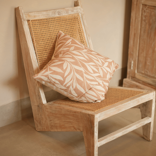 Wooden chair with a woven backrest and a patterned cushion in a warm-toned room.