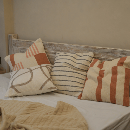 Decorative pillows on a bed with a wooden headboard in a bedroom setting.