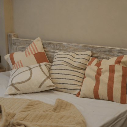 Decorative pillows on a bed with a wooden headboard in a bedroom setting.