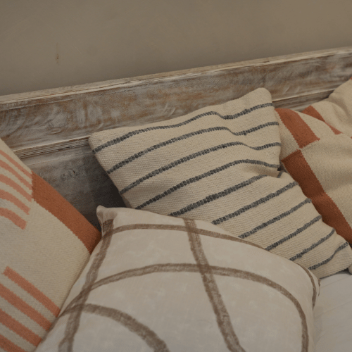 Decorative pillows with striped and geometric patterns on a wooden headboard.