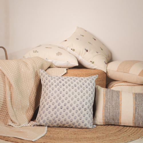 Collection of patterned pillows on a wooden surface with a neutral background