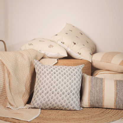 Collection of patterned pillows on a wooden surface with a neutral background