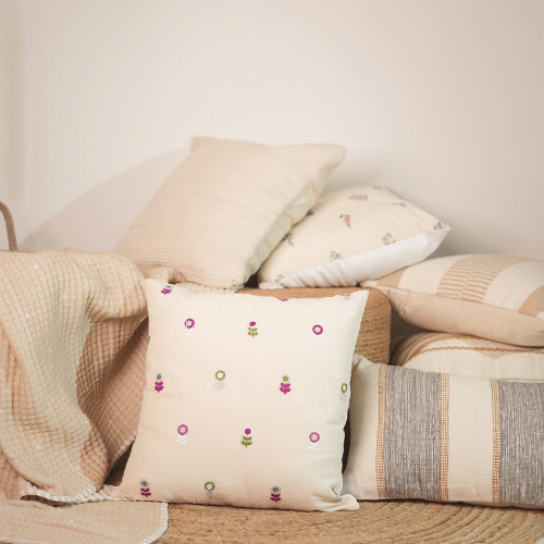 Decorative pillows with floral patterns on a sofa against a neutral wall.