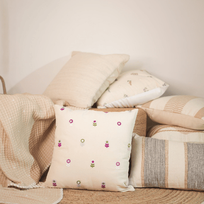 Decorative pillows with floral patterns on a sofa against a neutral wall.
