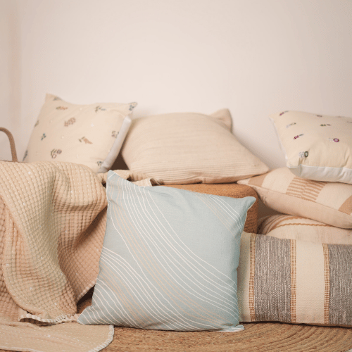 Beige and blue textured pillows on a sofa against a plain wall.