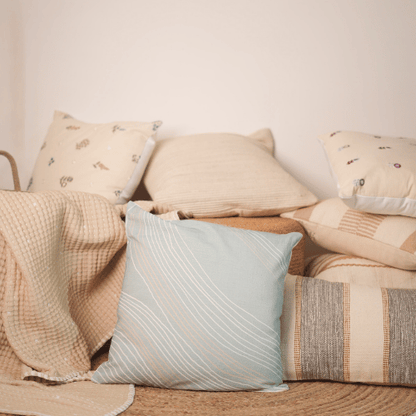 Beige and blue textured pillows on a sofa against a plain wall.