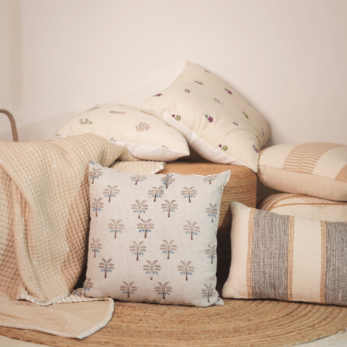 Collection of patterned pillows and a blanket on a wooden surface.
