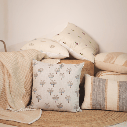 Collection of patterned pillows and a blanket on a wooden surface.