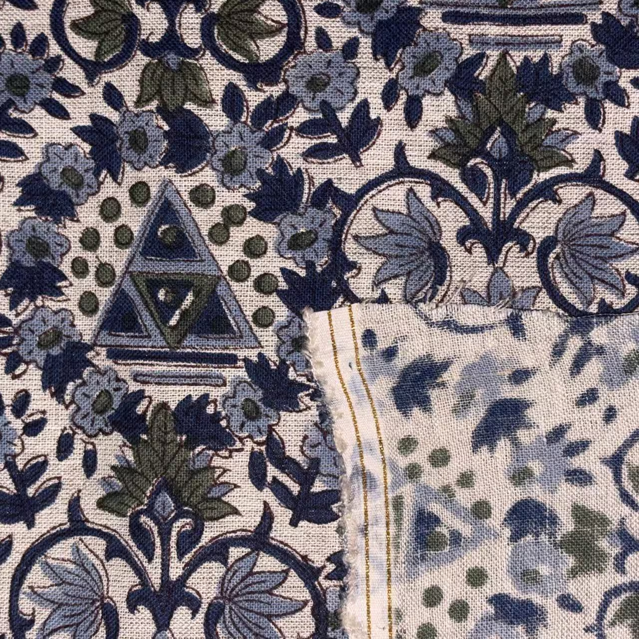 Close-up of a fabric with intricate blue and green floral patterns.