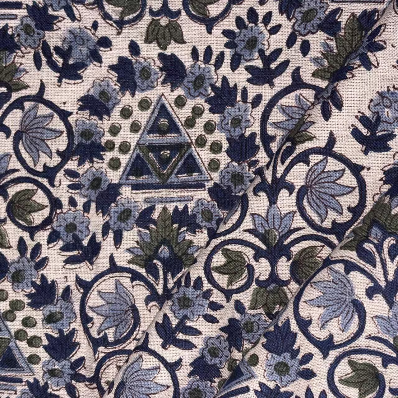 Close-up of a fabric with intricate floral and geometric pattern, featuring a prominent triangle design.